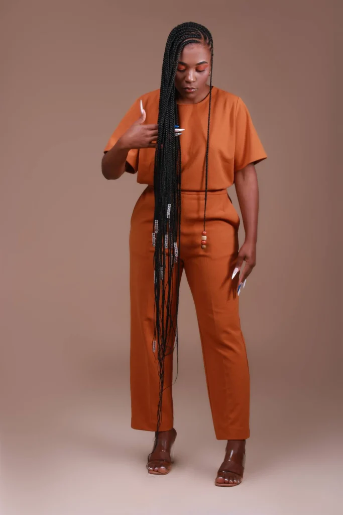 Modelo de corpo inteiro com tranças muito longas e conjunto cor de terra.