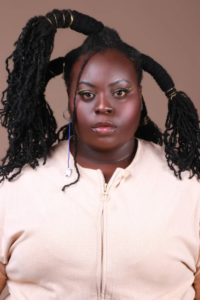 Retrato de modelo com cabelo texturizado preso em dois volumes com anéis dourados.