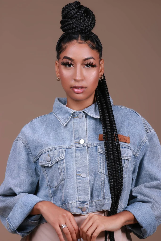 Penteado alto com coque entrançado e trança longa lateral.