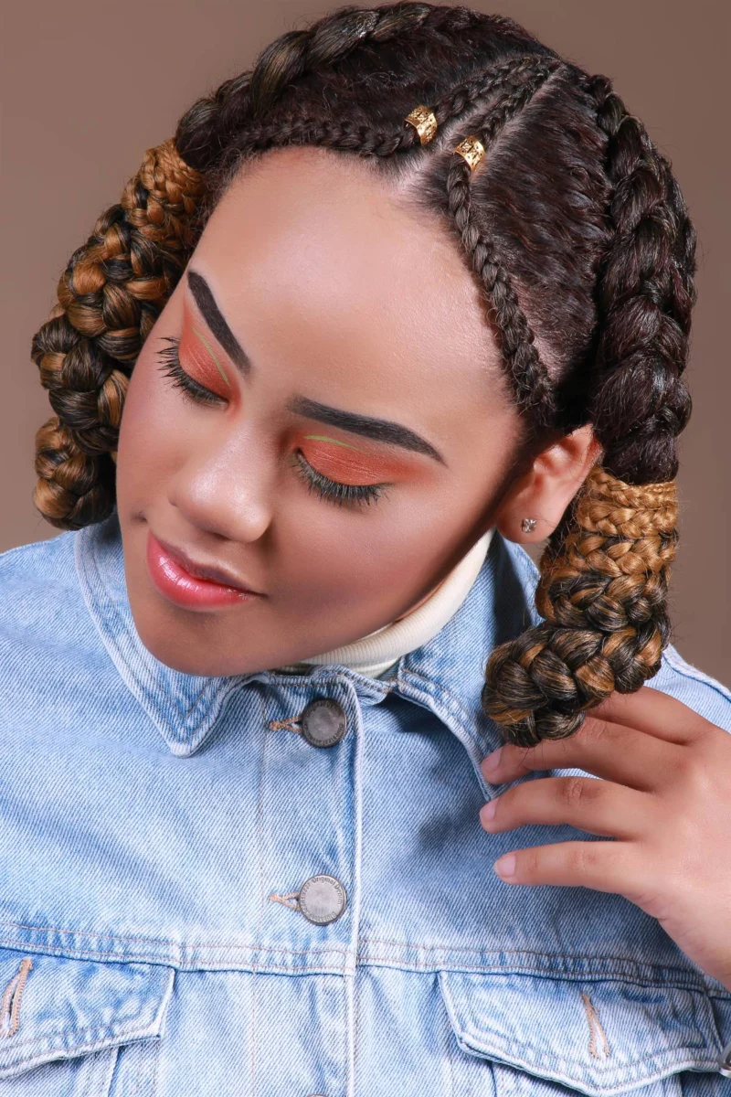 Penteado com duas tranças laterais volumosas e acessórios dourados.